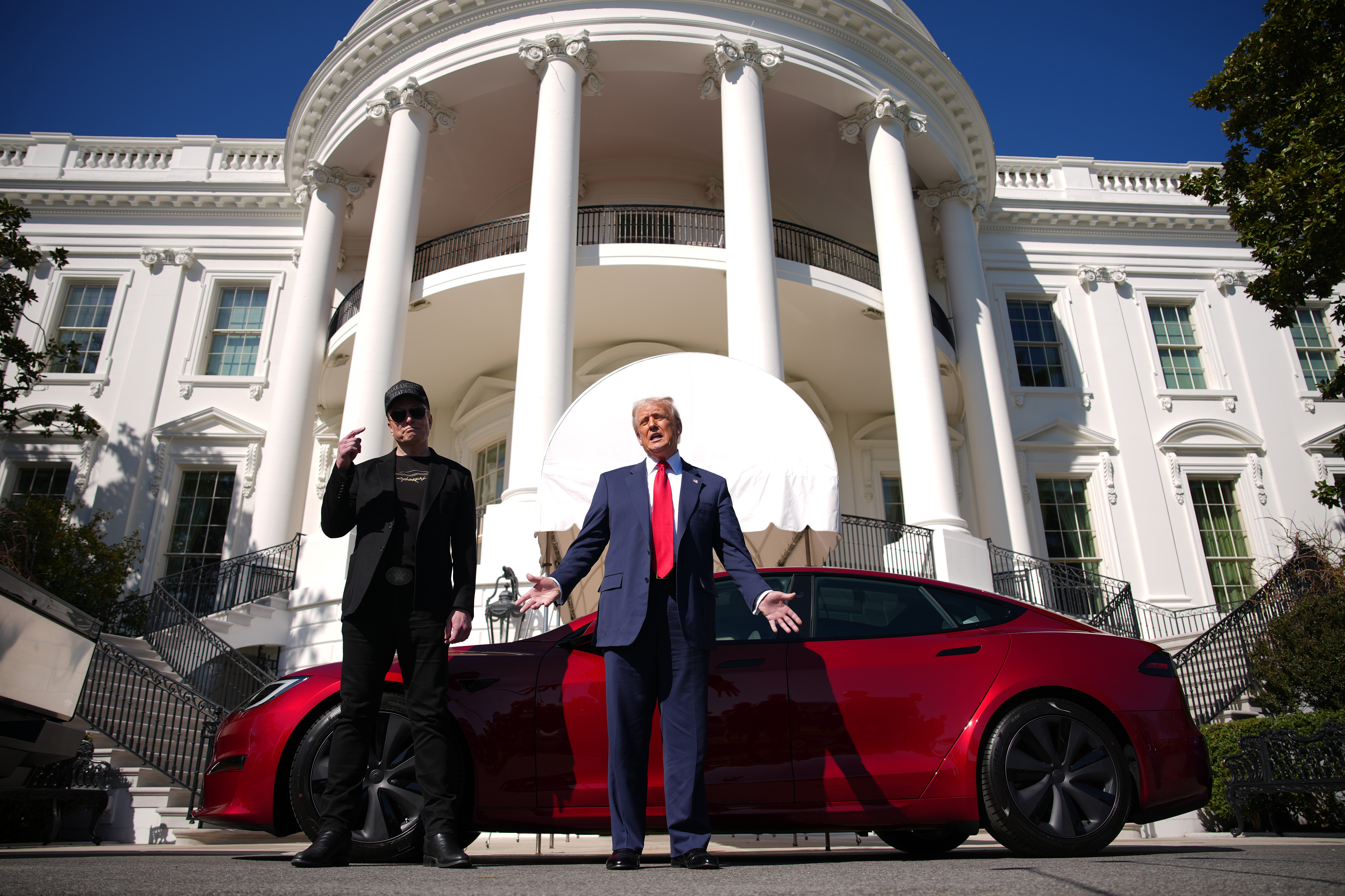 President Trump and Elon Musk standing by a Tesla in front of the White House.